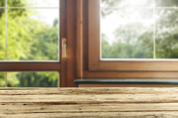 Wall Mural - dark brown wooden table top with copy space and wooden window background in home interior. green tre