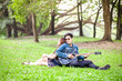 © kasipat - Asian couple in love playing acoustic song  guitar sitting on grass in the park
