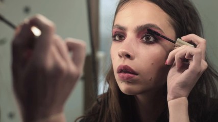 Wall Mural - Woman applying mascara on eyelashes with makeup brush. Young beautiful woman applying mascara makeup on eyes at. Beautiful brunette girl applying makeup on eyes in the morning time.Mascara Brush.