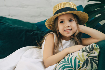 Preschool girl is lying on the green sofa. Preschool girl is on vacation indoors.