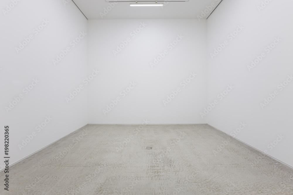 Obraz na płótnie A view of a white painted interior of an empty room or an art gallery with a fluorescent lighting and concrete floors w salonie