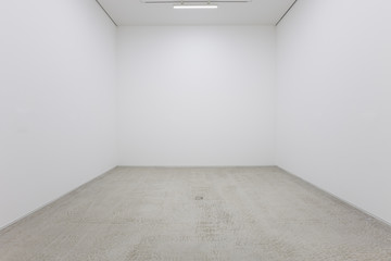 a view of a white painted interior of an empty room or an art gallery with a fluorescent lighting an