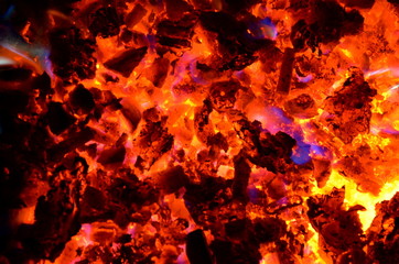 Poster - 
Violet tongues of flame from burning non-ferrous metals break through the hot coal.