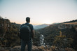 © Cavan Images - Rear view of man with backpack standing on mountain against clear sky during sunset