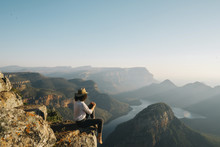 Side View Of Woman Looking At View While Sitting On Mountain Against Clear Sky