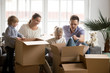 © fizkes - Young happy family with kids packing boxes on moving day together sitting on sofa in modern living room, kids with parents settling in new home, children helping to unpack stuff after relocation