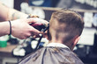 © Artem - Barber is shaving a hair to Caucasian boy in barbershop.