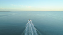 AERIAL: Fishing Boat Leaves A Trail In Ocean Water As It Speeds Towards Horizon.