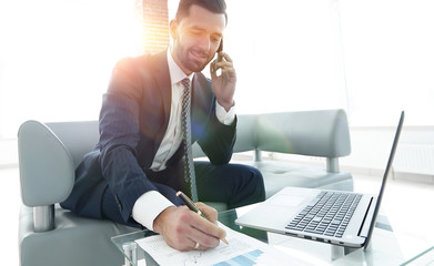 Businessman talking on smartphone about financial documents