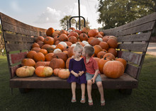 Brother Kissing Sister While Sitting Against Pumpkins On Cart