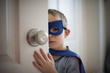 © Cavan Images - Close up of boy in superhero costume while standing by the door at home