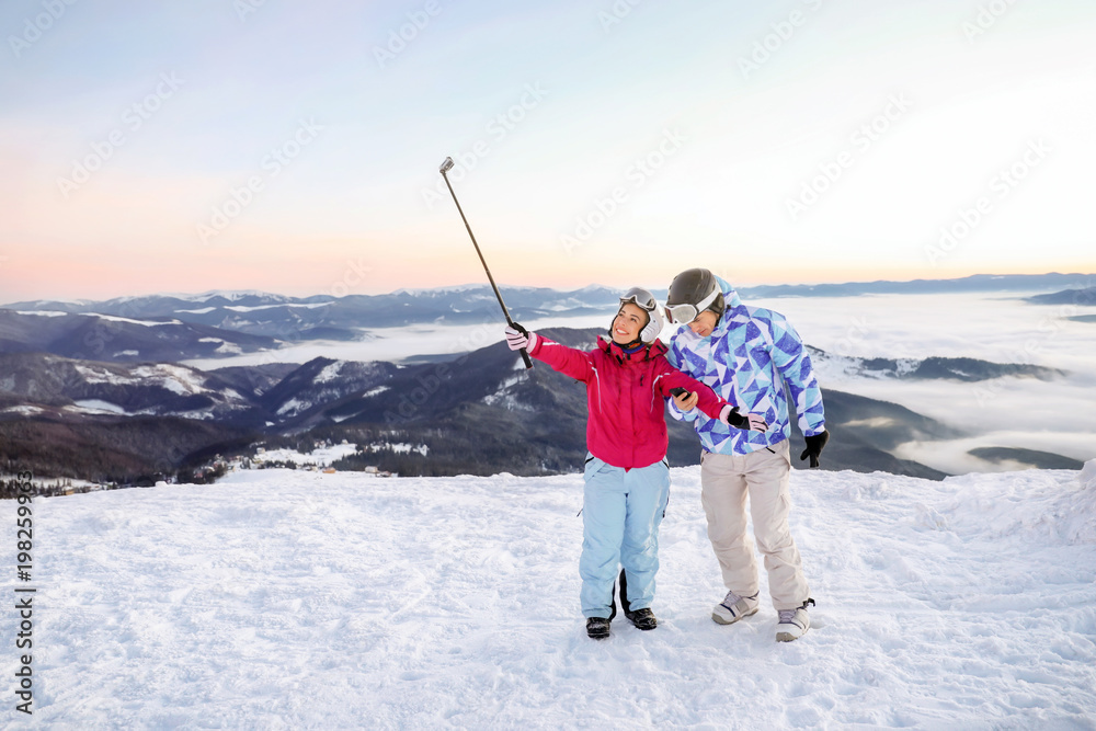 Couple taking selfie at snowy ski resort. Winter vacation