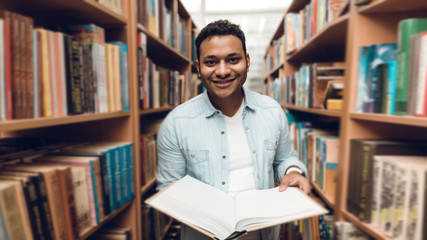 Wall Mural - Ethnic indian mixed race student in book aisle of library.