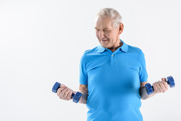 portrait of smiling senior man with dumbbells isolated on grey