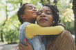 © Mladen - African American mother hugging her little daughter in meadow.