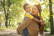 © Mladen - African American mother carrying his daughter on piggyback in park.