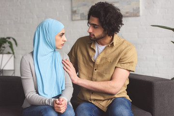 Canvas Print - muslim boyfriend hugging girlfriend in hijab in living room