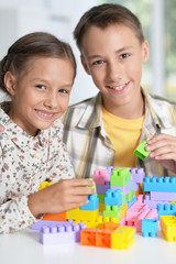 Wall Mural - Brother and sister playing with plastic blocks