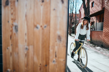 Wall Mural - Young modern woman riding a bicycle on the street.