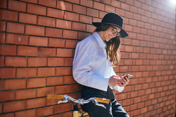 Wall Mural - Woman using smart phone and leaning on the bicycle.