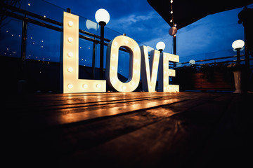Wall Mural - Word love from big, letters with glowing light bulbs on a dark b