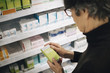 © Maskot - High angle view of senior female customer examining medicine by rack at pharmacy store