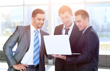 business colleagues looking at a laptop, standing in the lobby o