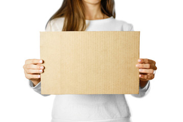 Wall Mural - A young girl in a white jacket holding a piece of cardboard. Prepared for your text