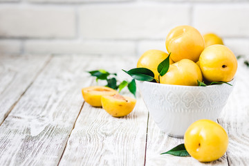 Ripe yellow plums on wooden background. Selective focus, space for text. 