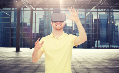 Wall Mural - 3d technology, virtual reality, entertainment and people concept - happy young man with virtual reality headset or 3d glasses playing game over industrial empty room and city panorama background