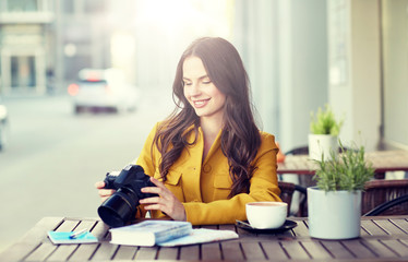 Sticker - travel, tourism, photography, leisure and people concept - happy young tourist woman or teenage girl with digital camera photographing and drinking cocoa at city street cafe terrace