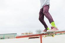 A Close-up Of A Teenager's Leg Of A Skateboarder Glides On A Skateboard Along The Railing In The Skatepark. The Concept Of Moving Forward At A Young Age. Teenage Sports