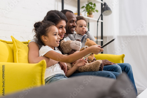 Cuadros en Lienzo beautiful young family watching tv together on couch