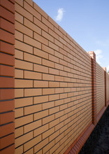 Beautiful High Fence With Yellow Bricks On The Background Of The Sky