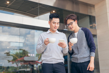 Two smiling businessmen walking and talking in the city