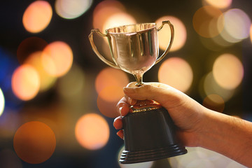 Wall Mural - winner hold trophy with abstract bokeh light background