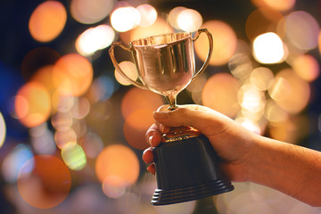 Wall Mural - winner hold trophy with abstract bokeh light background