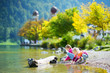 © MNStudio - Adorable sisters playing by Konigssee lake in Germany on warm summer day. Cute children having fun feeding ducks and throwing stones into the lake.