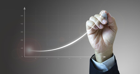 close up of a businessman’s hand drawing an exponential line curve showing of business growth and su