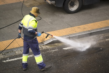 Wall Mural - sweeper gardener  cleaning  the city street with pressure water