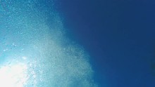 Man Diving In Swimming Pool, Sea Or Ocean Underwater View. Swimmer Jumping In To The Water. Wave And Sun Underwater Over Blue Sunny Sky Background. Shot With GOPRO HERO4 4K UHD Video.