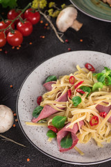 Wall Mural - Italian spaghetti. Tagliatelle pasta with ham. Selective focus. Black background. Top view