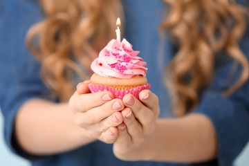 Wall Mural - Woman holding beautiful birthday cupcake with candle, closeup