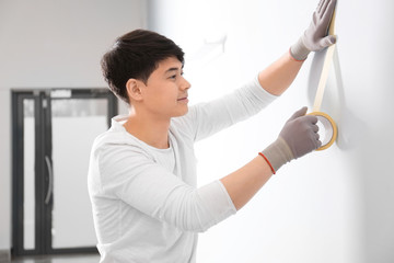 Canvas Print - Male decorator working with tape indoors