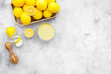 Wall Mural - Lemon curd. Sweet cream for desserts near lemons and juicer on grey background top view copy space