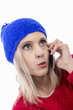 blonde woman with blue winter hat talking on phone