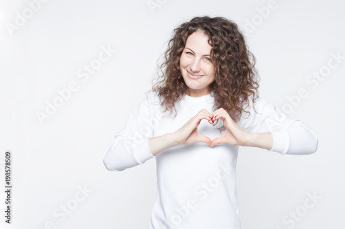 Fotografía Studio shot of beautiful Caucasian lady holding hands in shape of heart, symbolizing love, peace and unity