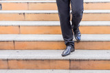 Fototapeta Na drzwi - Businessman legs taking step on a lower level on a stairs - bad business investment decision concept