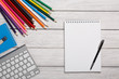 White notepad, keyboard, color pencils on a white table