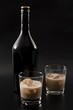 Coffee liqueur and alcoholic beverages based on milk and whiskey concept with Irish cream bottle and glasses with ice isolated on dark black background